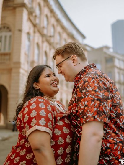 A close-up of a couple sharing a happy, intimate moment on the streets of Mumbai, framed by the city's classic architecture.