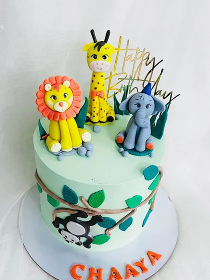 A sweet and simple jungle cake with three adorable animal toppers: a lion, a giraffe, and an elephant.