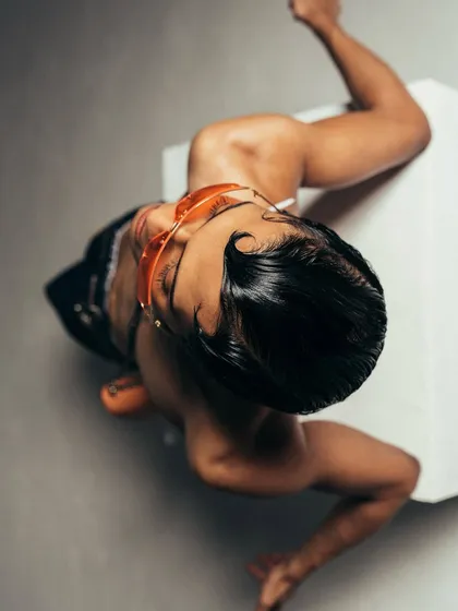 An unconventional overhead angle from a Calvin Klein shoot. This perspective creates a graphic composition, focusing on the model's pose, styled hair, and accessories.