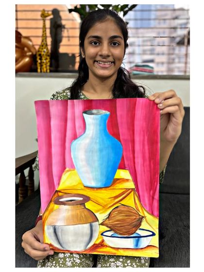 An intermediate grade exam student with her still life painting, showing a skillful arrangement of a vase, pot, and coconut.