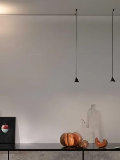 A pair of Filomena pendants provide focused task lighting over a kitchen counter, their minimalist form ensuring they don't distract from the overall design of the space.