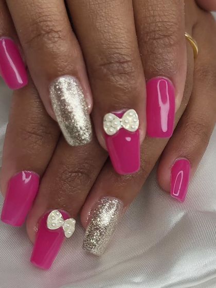 A cute and playful design featuring a bright pink base with gold glitter accent nails. The hand-sculpted 3D bows with pearl centers add a touch of sweetness.