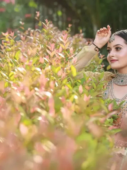 A dreamy portrait taken in a garden, with the bride surrounded by soft pink and green foliage. The natural light is soft and flattering.