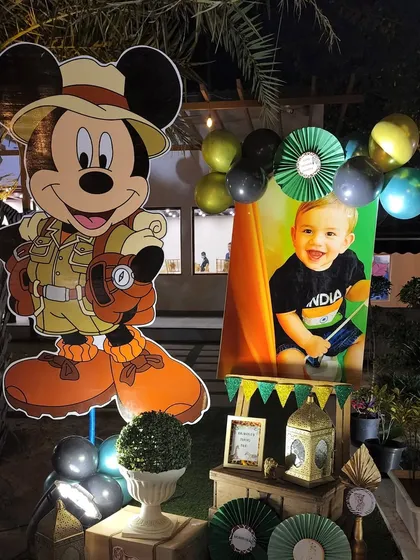 A personalized welcome area for the safari party. It features a large cutout of Mickey Mouse as a safari explorer next to a photo of the birthday boy, creating a sweet, personal touch.