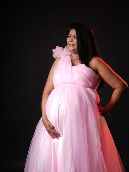 Using studio lighting, I can create a more dramatic and artistic portrait. This mom-to-be looks powerful and serene in this pink gown against a dark background.
