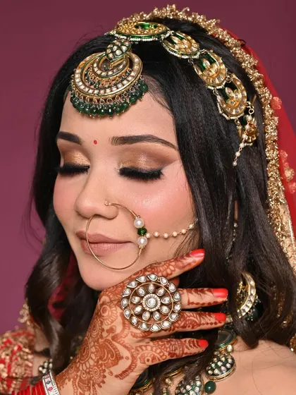 A close-up of a modern bridal look with soft, brown smokey eyes and a nude lip. The intricate henna and jewelry are complemented by the flawless makeup application.