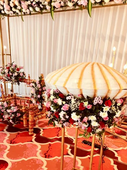 A side view of the naming ceremony stage, showing the cradle and the decorative floral stands against the elegant backdrop.