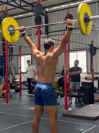 A competitor shows impressive strength and form, completing a heavy lift overhead during the throwdown.