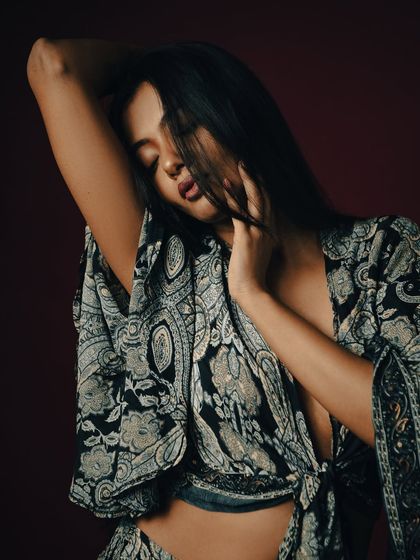 An intimate and expressive pose, with the model's hair partially obscuring her face.