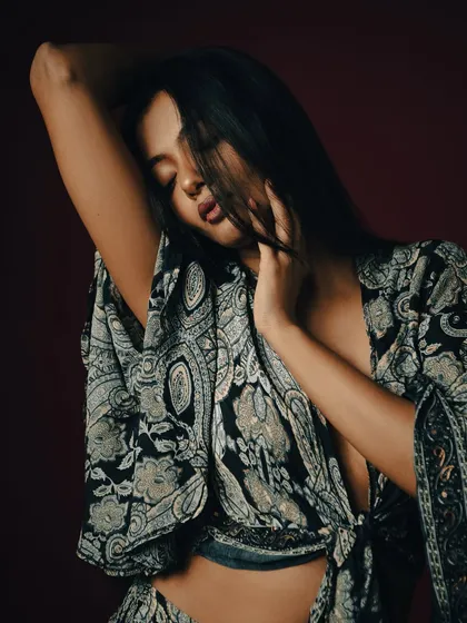 An intimate and expressive pose, with the model's hair partially obscuring her face.