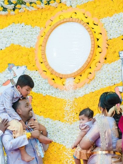 A beautiful, wide shot of a naming ceremony, showing the family gathered around the baby during a key ritual. The flower decor adds a festive touch.