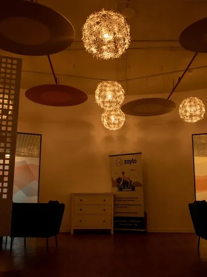 A lounge in a common cafe area, featuring warm, ambient lighting from spherical pendant lights and decorative screens for privacy.