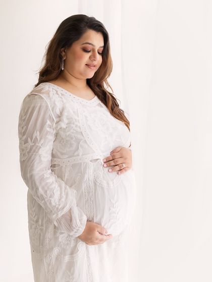 A gentle and introspective portrait. The soft white lace dress and the bright, clean background give this image a feeling of purity and peace.