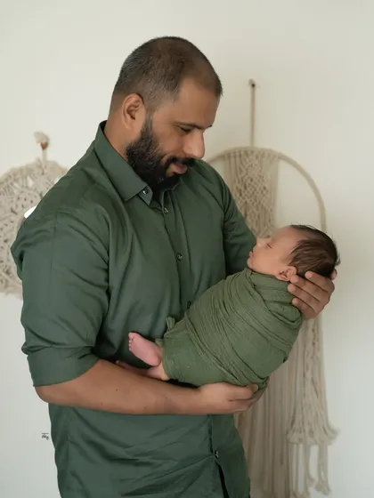 A father looking down at his newborn, swaddled in a lovely olive green wrap. This is a quiet, strong portrait that captures the beginning of a lifelong bond.