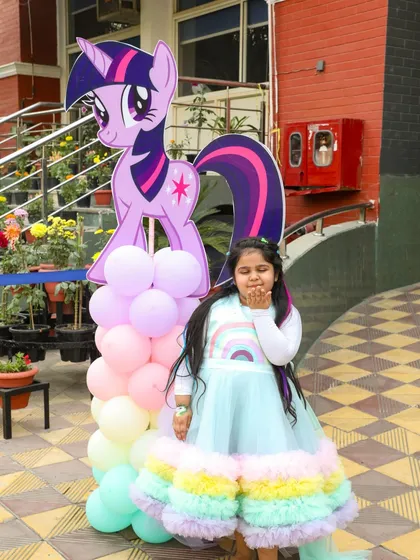 The birthday girl posing with a life-sized Twilight Sparkle cutout, part of the immersive decor for her Little Pony theme.