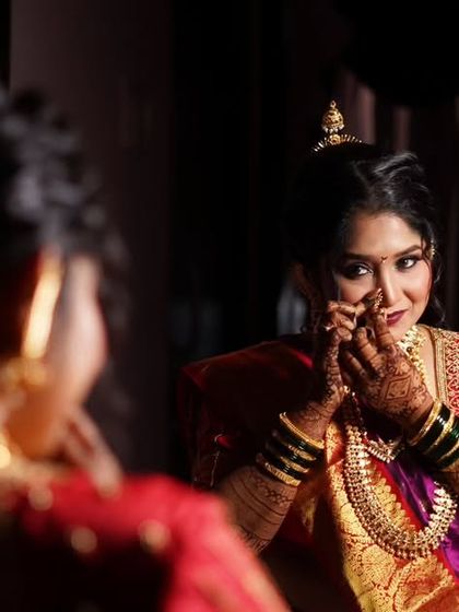 A candid moment in the mirror. This Maharashtrian bride in her vibrant Nauvari saree catches a glimpse of her final look, a blend of tradition and personal style.