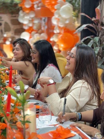 Guests enjoying an activity at the Hermès-themed baby shower, writing wishes for the parents-to-be. The atmosphere is filled with laughter and friendship.