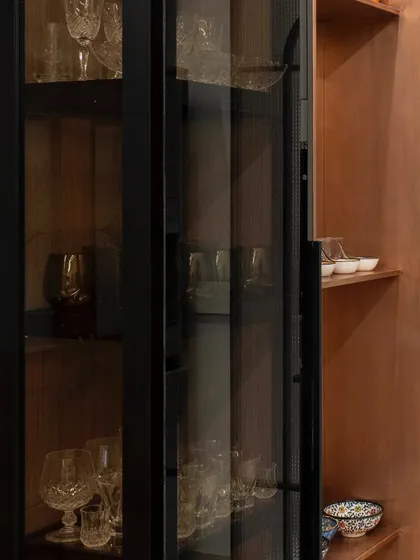 A close-up of the crockery unit, showing the texture of the glass and the warm wood interior. This combination of materials adds depth and sophistication to the storage design.