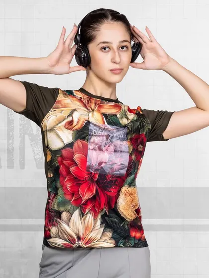 A model wearing a floral-printed fitness t-shirt listens to music on headphones. This shot combines fitness with a lifestyle element, making the brand feel more accessible and fun.