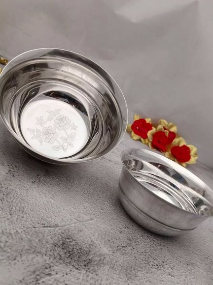 A pair of stainless steel bowls with a silver finish and a floral design etched at the bottom, an elegant and useful return gift.