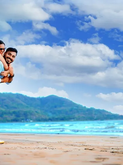 A fun and playful piggyback ride on the beach. This pre-wedding photo captures the couple's joyful energy against a backdrop of blue skies and gentle waves, showing a lighthearted side to their relationship.