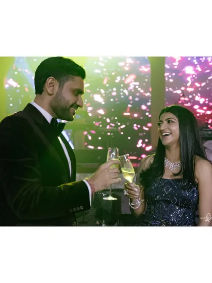 Tanya and Shivam clink their champagne glasses. Their eye contact and happy laughter make this a perfect "cheers" moment, full of celebration and love.