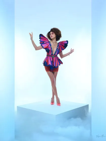 An artistic shot for a designer collection, focusing on structural and colourful garments. The model's pose and the butterfly-like shoulders of the top create a powerful, high-fashion statement.