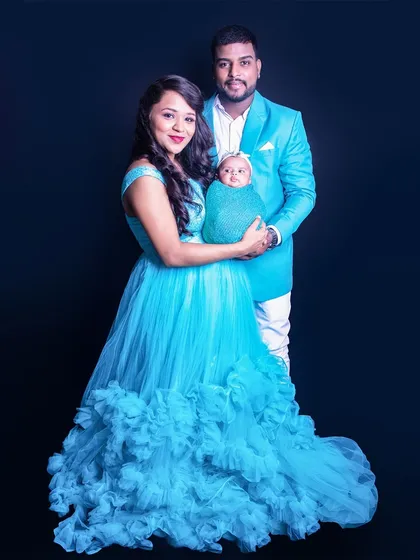 A full-length family portrait where the parents' coordinated blue outfits complement the baby's swaddle. This shows how we can style the entire family for a cohesive and beautiful photo.