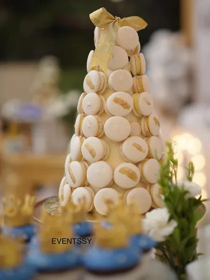 A tower of elegant white and gold macarons, a sophisticated dessert choice for a royal-themed party.