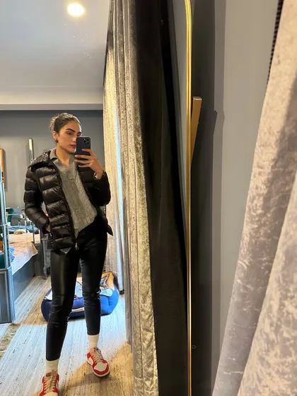 An edgy winter look with a puffer jacket, grey sweater, and faux leather pants.