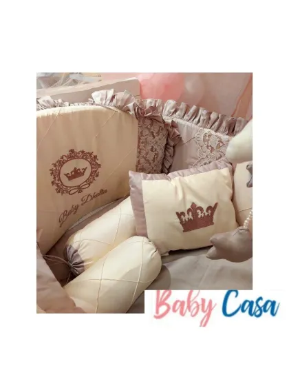 A close-up of a royal-themed bedding set in dusty rose. This image highlights the personalized embroidery, crown motifs, and the mix of textures with lace and quilted details.