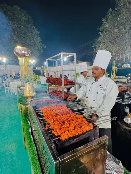 My chef at the barbecue counter, grilling skewers of bright red chicken tikka, a popular and flavorful choice for any celebration.