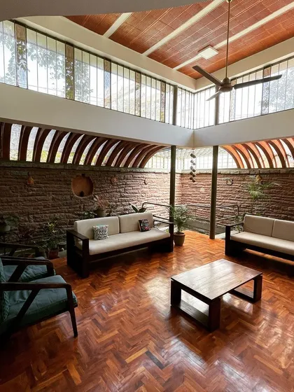 Is it a living room or a room with life? This space is defined by light. Large windows and a vaulted ceiling with exposed clay tubes create an airy, open atmosphere, while the brick wall adds warmth and texture.