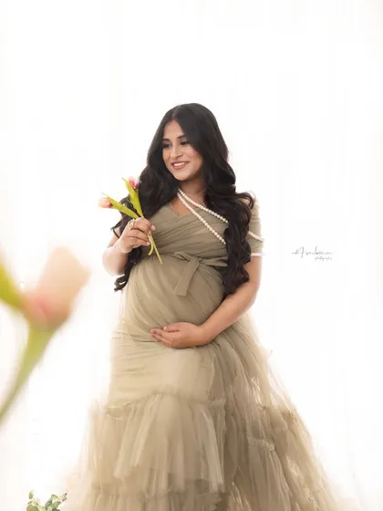 A beautifully framed shot, with a flower in the foreground adding depth and an artistic touch. Her happy, candid expression makes this a delightful and memorable portrait.