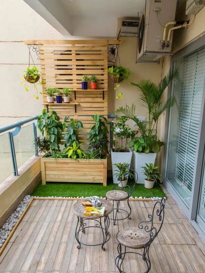 A charming balcony garden featuring a wooden planter box and a vertical trellis for climbing plants. The combination of wood, greenery, and classic wrought-iron furniture creates a timeless look.