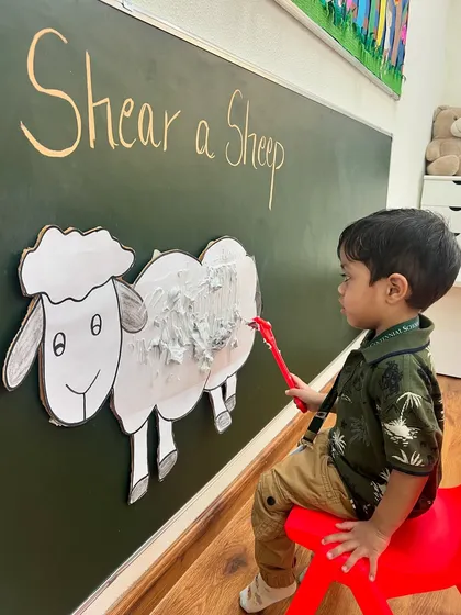 Another student takes a turn shearing our fluffy friend. Role-playing activities like this make learning about different concepts, like where wool comes from, memorable and fun.