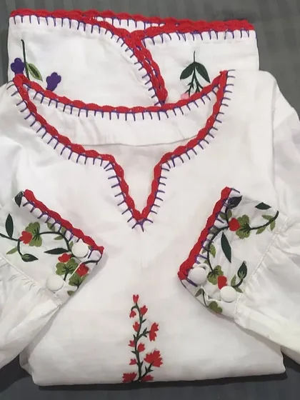 We added a custom red crochet lace trim to the neckline and cuffs of this beautiful embroidered white top. It's a great way to add a pop of color and a handmade detail.