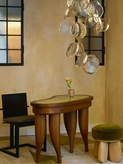 The Bocci 141 series installed as a delicate, cascading pendant over a console table. Each piece is crafted by pouring hot glass, resulting in a unique, winged shape that feels both simple and cinematic.