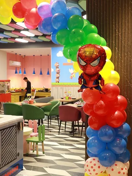 A colorful superhero-themed balloon arch with a Spiderman balloon, marking the entrance to the party area and our vibrant cafeteria.