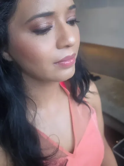 A close-up of a soft and natural makeup look. The skin is fresh and dewy, with a hint of color on the cheeks and a glossy nude lip.