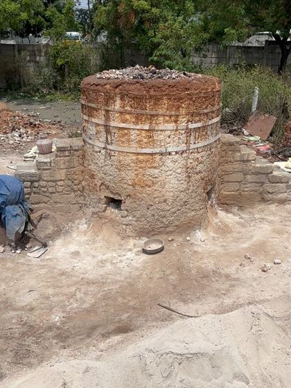 A full view of the vertical lime kiln. These structures are marvels of traditional engineering, designed to efficiently burn limestone using local fuel sources, creating a low-carbon building material.