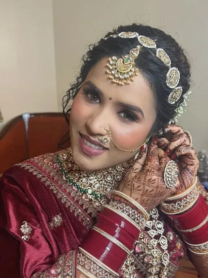 A candid moment of the bride getting ready. The traditional chooda and nath are essential elements of her stunning North Indian bridal look.