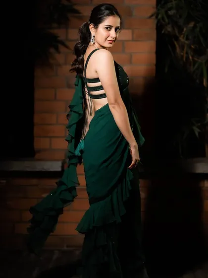 This emerald green saree gown is my modern take on a classic silhouette, designed for actress Ashika Ranganath. It combines the ease of a gown with the elegance of a saree, featuring cascading ruffles and a stylish strappy back for a contemporary cocktail look.