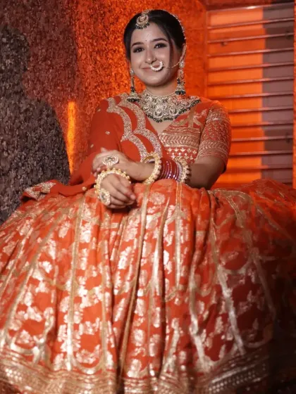A candid shot of the bride in the orange-red banarasi lehenga, showing how the color glows under warm lighting.