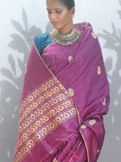 A luxurious purple silk sari with an ornate, woven border, perfect for festive occasions and celebrations.