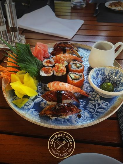 A beautiful platter of assorted sushi and nigiri, featuring shrimp, unagi, and spicy tuna rolls. Served on a traditional blue and white ceramic plate, it's a feast for the eyes and the palate.
