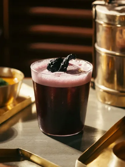 A deep purple cocktail made with jamun or berries. The dark, rich color is the hero of this shot, suggesting a deep and complex flavor.