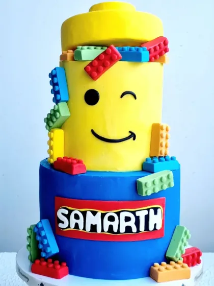 A fun, two-tiered Lego-themed cake. I teach how to create the iconic Lego brick shapes from fondant and assemble them on the cake for a playful, colorful design.