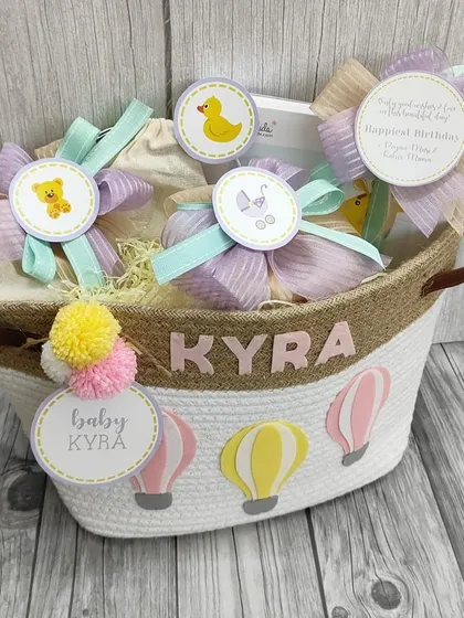 A first birthday surprise basket for baby Kyra. This personalized jute basket is filled with thoughtfully curated baby gifts, each adorned with a cute tag.