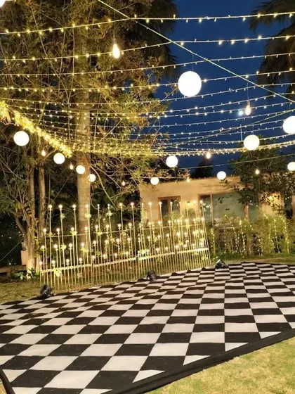 We transform outdoor spaces into magical party zones. This custom black-and-white checkered dance floor, set under a canopy of string lights and paper lanterns, created an inviting and high-energy atmosphere for a Sangeet night.